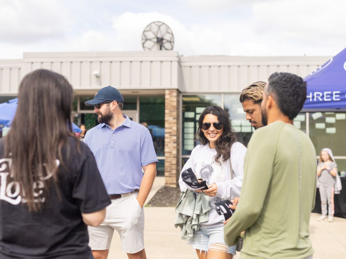 A group standing outside talking after a service, in everything from a polo and shorts to a sweatshirt.